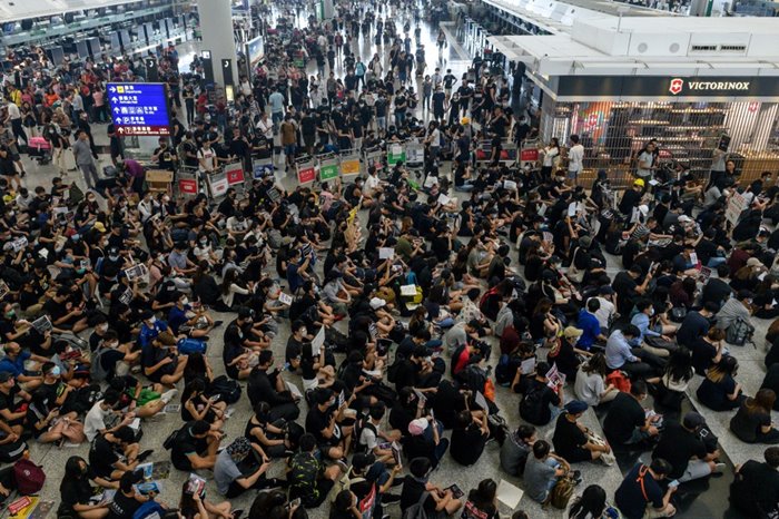 &lt;i&gt;กลุ่มผู้ประท้วงเรียกร้องประชาธิปไตยชาวฮ่องกง (ด้านล่าง) ปิดกั้นพื้นที่เข้าสู่ประตูขาออก ของสนามบินฮ่องกง วันอังคาร (13 ส.ค.) &lt;/i&gt; 