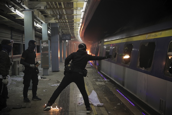 <i>นักศึกษาสวมหน้ากากผู้หนึ่งขว้างระเบิดขวดน้ำมันเข้าไปภายในขบวนรถไฟ ซึ่งจอดอยู่ภายในสถานีรถไฟใต้ดิน “ไชนีส ยูนิเวอร์ซิตี้” ในฮ่องกงเมื่อวันพุธ (13 พ.ย.) </i>