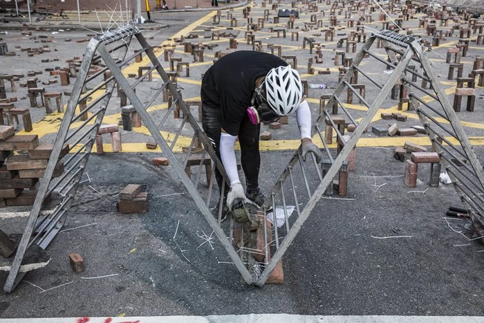 <i>ผู้ประท้วงเทซีเมนต์เพิ่มความแข็งแรงให้เครื่องกีดขวาง บนถนนด้านนอกของมหาวิทยาลัยโปลิเทคนิค ในฮ่องกงเมื่อวันศุกร์ (15 พ.ย.) </i>