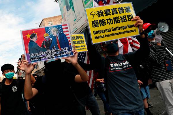 กลุ่มประท้วงต่อต้านรัฐบาลโบกธงชาติอเมริกาขณะเดินขบวนใน Sheung Shui เขตชายแดนฮ่องกงเมื่อวันอาทิตย์ที่ 5 ม.ค. 2020 (ภาพ รอยเตอร์ส)