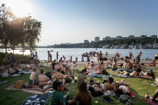 ประชาชนนอนอาบแดดกันริมทะเลสาบแห่งหนึ่งในกรุงสตอกโฮล์ม เมื่อวันที่ 24 มิถุนายน ในขณะที่สวีเดนไม่เคยมีคำสั่งห้ามรวมตัวของคนหมู่มากหรือบังคับให้สวมหน้ากากป้องกันโควิด-19 แต่อย่างใด