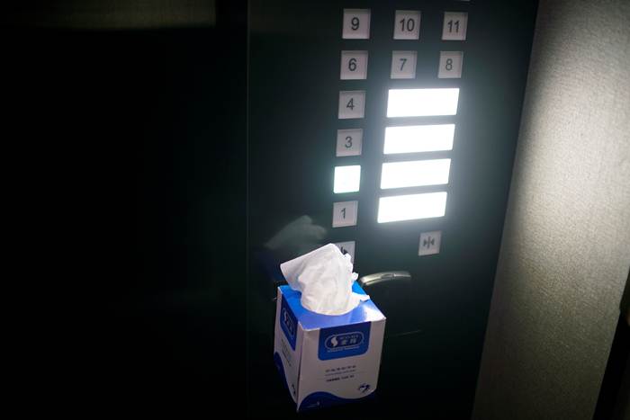 เจ้าหน้าที่โรงแรมในนครเซี่ยงไฮ้นำกล่องกระดาษทิชชู่ มาติดตั้งไว้ข้างลิฟท์หลังจากที่เกิดการแพร่ระบาดครั้งใหม่ในจีน ภาพเมื่อวันที่ 24 มิ.ย.2020 (ภาพ รอยเตอร์ส)