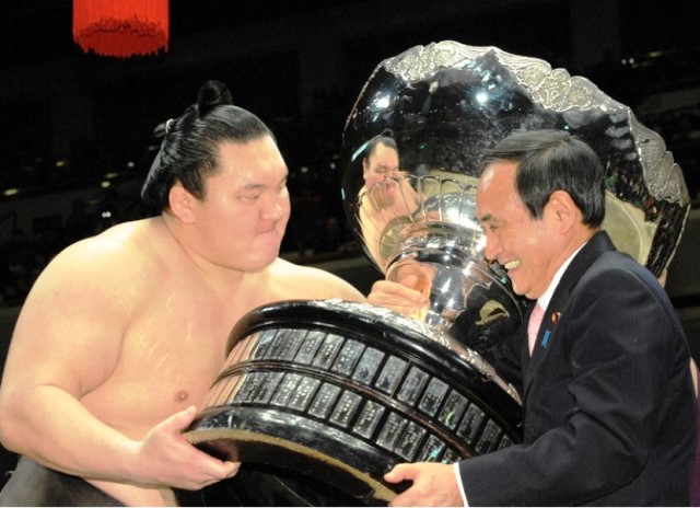 นายซูงะมอบถ้วยรางวัลจากนายกรัฐมนตรีให้กับฮาคุโฮ แชมป์มวยปล้ำระดับชาติ เมื่อ 26 ม.ค. 2014