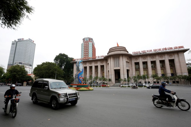 ชาวเวียดนามขับรถผ่านอาคารธนาคารกลางในกรุงฮานอย. -- Reuters.