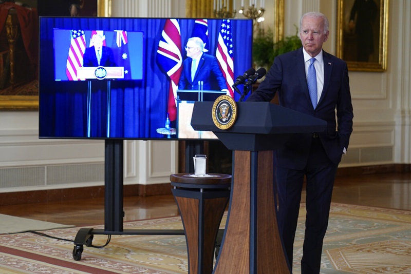 ประธานาธิบดีโจ ไบเดน ของสหรัฐฯ ยืนข้างๆ จอภาพที่แสดงภาพของ นายกรัฐมนตรีสหราชอาณาจักร บอริส จอห์นสัน (ซ้ายสุด) และนายกรัฐมนตรีออสเตรเลีย สกอตต์ มอร์ริสัน ระหว่างการประกาศจัดตั้งกลุ่มพันธมิตรทางทหารกลุ่มใหม่ของ 3 ประเทศนี้ ซึ่งใช้ชื่อว่า AUKUS (ออคัส) 