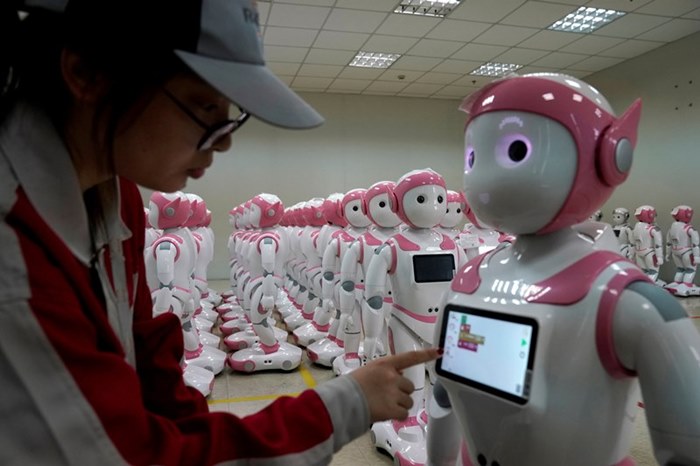 คนงานกำลังตรวจสอบงานขั้นสุดท้ายการผลิตหุ่นยนต์อัจฉริยะที่สื่อสารโต้ตอบกับมนุษย์ ‘iPal social robot’ ที่โรงงานในเมืองซูโจว มณฑลเจียงซู ภาพเมื่อปี 2018 (แฟ้มภาพรอยเตอร์)