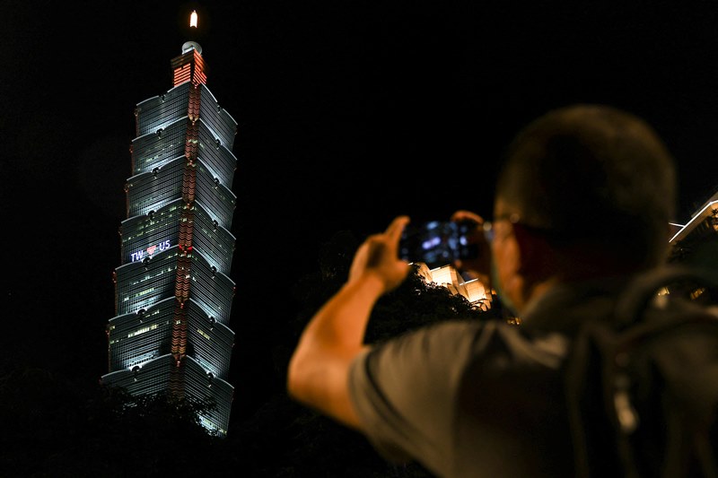 ชาวไต้หวันถ่ายภาพป้าย ‘โปรอเมริกา’ ที่ติดบนตึกระฟ้าสัญลักษณ์ไต้หวัน (ภาพรอยเตอร์)