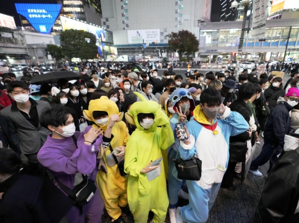 ผู้คนที่แต่งกายด้วยชุดฮาโลวีนเดินผ่านย่านชิบูย่าของโตเกียวในวันที่ 31 ต.ค.2021 โดยสวมหน้ากากอนามัยเพื่อป้องกันไวรัสโคโรนา (เกียวโด)