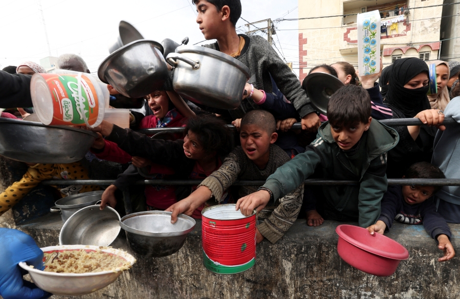 เด็กๆ ชาวปาเลสไตน์รอรับอาหารจากครัวการกุศลที่เมืองราฟาห์ วันอังคาร (13 ก.พ.) ขณะที่เกิดภาวะขาดแคลนอาหารกันอยู่ทั่วไปในเมืองนี้ ซึ่งมีคนอพยพหนีตายเข้ามาพำนักอาศัยเป็นล้านคน