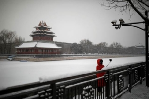 หญิงจีนกำลังถ่ายภาพเซลฟี่หลังหิมะตกบริเวณนอกพระราชวังต้องห้าม กรุงปักกิ่ง ภาพ 6 ก.พ. 2020 (ไชน่าเดลี่/รอยเตอรส์)