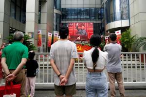 ผู้คนชมการถ่ายทอดประธานาธิบดี สี จิ้นผิง ของจีนกล่าวปราศรัยที่ประตูเทียนอันเหมิน จากจอยักษ์ในเมืองเซี่ยงไฮ้ วันพฤหัสบดี (1 ก.ค.)