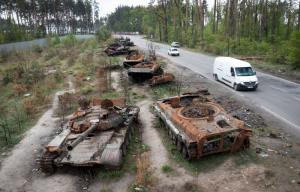 รถราแล่นผ่านซากรถถังรัสเซียหลายคันที่ถูกทำลายเสียหายยับระหว่างการสู้รบกับฝ่ายยูเครนเมื่อไม่นานมานี้ ในเขตหมู่บ้านดมิตริฟกา ใกล้ๆ กรุงเคียฟ เมืองหลวงของยูเครน  (ภาพนี้ถ่ายในวันจันทร์ 23 พ.ค.)